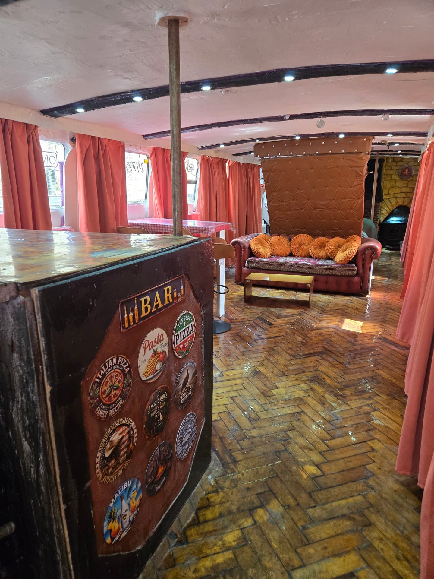 Quirky bar lounge with vintage Italian pizza memorabilia, comfortable seating, and ambient lighting. Perfect for entertaining guests in this unique entertainment space.